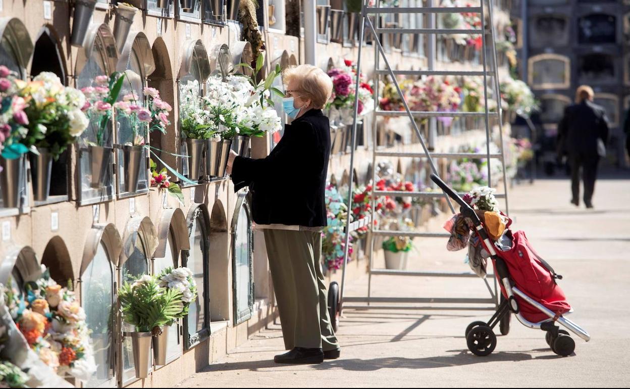 Una mujer deja flores en un cementerio. 