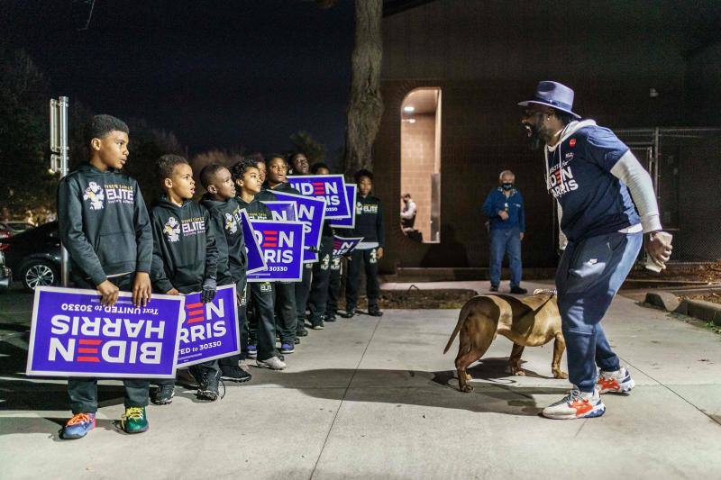 Un grupo de niños que apoyan al candidato presidencial Joe Biden sostienen carteles en la acera enfrente de un lugar de votación en Minneapolis, Minnesota.