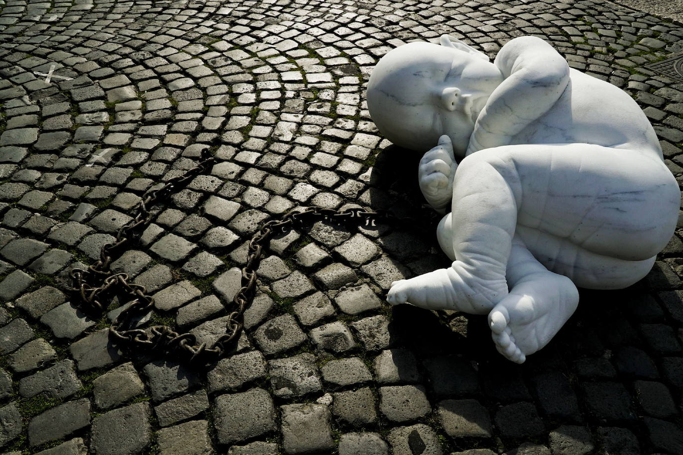 Una escultura en mármol blanco, que representa a un niño acurrucado y con una muñeca encadenada, ha sido abandonada en el centro de la plaza Plebiscito, en Nápoles. 