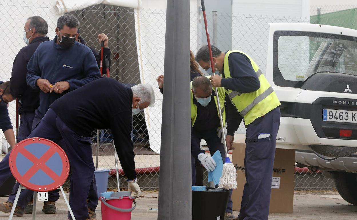 Operarios se disponen a adecentar el hospital de campaña de La Fe con cubos y fregonas tras las lluvias.