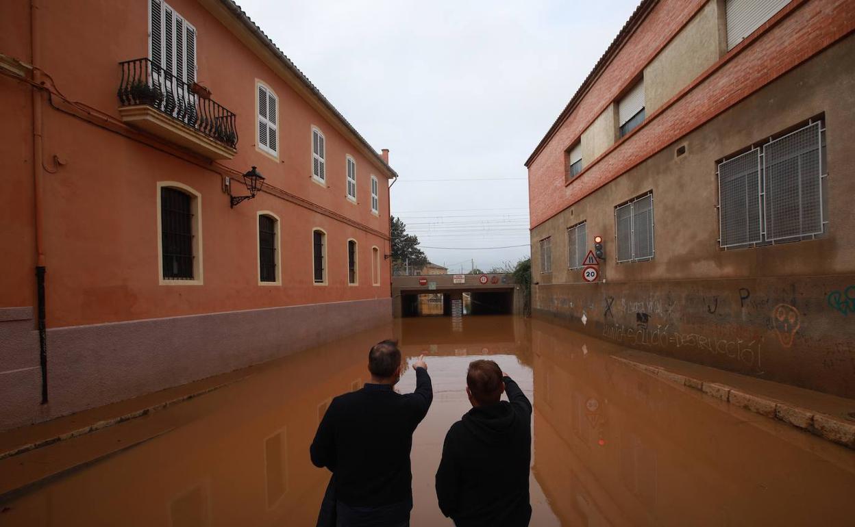 Dos hombres observan un paso inundado en Carcaixent. 