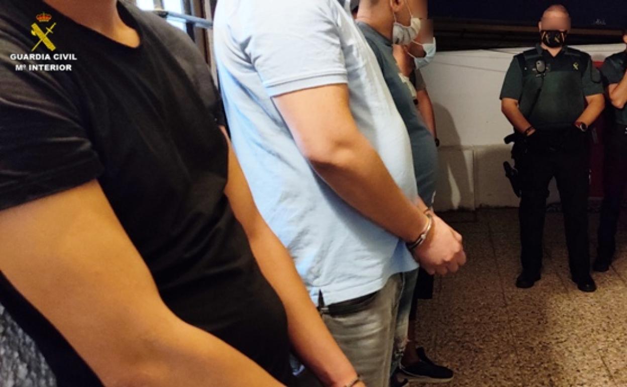 Imagen de los cuatro detenidos, esposados y escoltados por agentes de la Guardia Civil. 