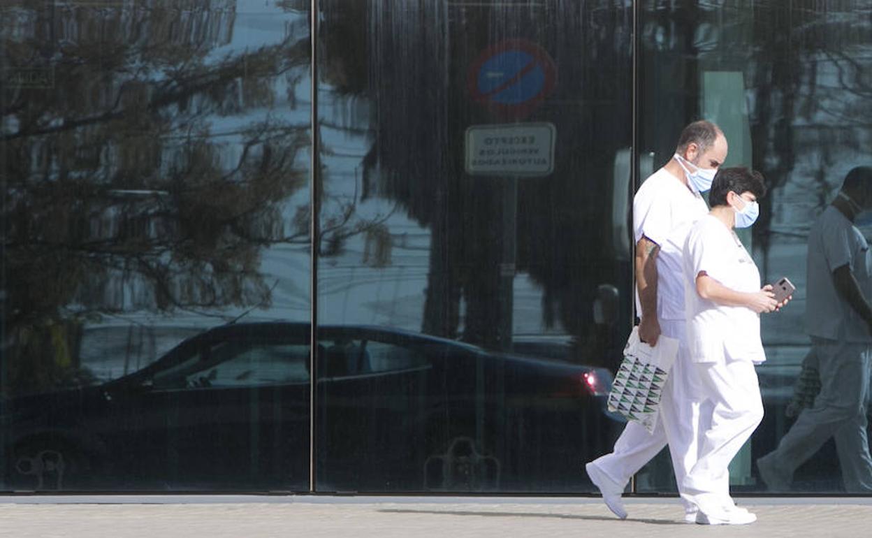 Dos sanitarios caminan ante la entrada del Hospital La Fe de Valencia. 