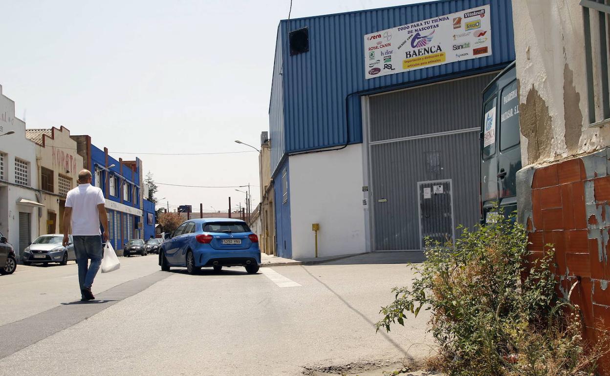 Un hombre camina por la calle de un polígono industrial. 