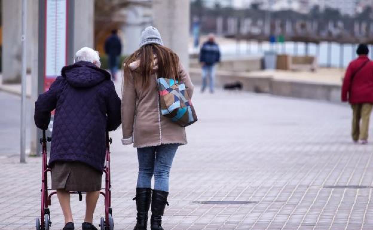 Una joven pasea con una mujer con movilidad más reducida.