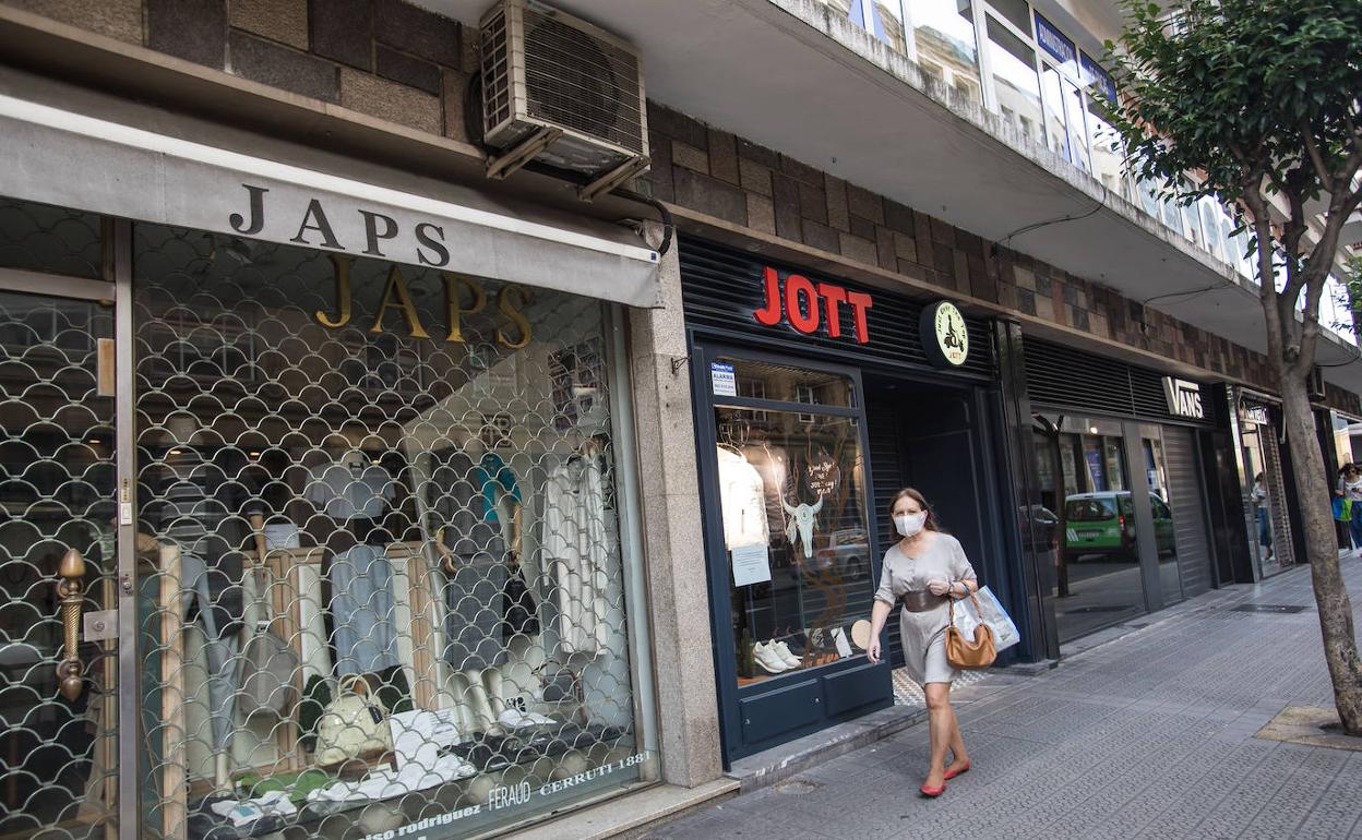 Una mujer pasea frente a tiendas cerradas por la pandemia.