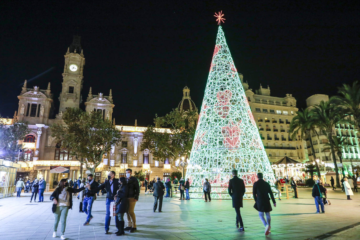 El alcalde Ribó ha asistido esta tarde al encendido en la plaza del Ayuntamiento, acompañado por las falleras mayores de Valencia, Consuelo Llobell y Carla García. La iluminación se estrena en la ciudad con quejas por el escaso gasto frente al aumento en otras ciudades para ayudar al comercio.