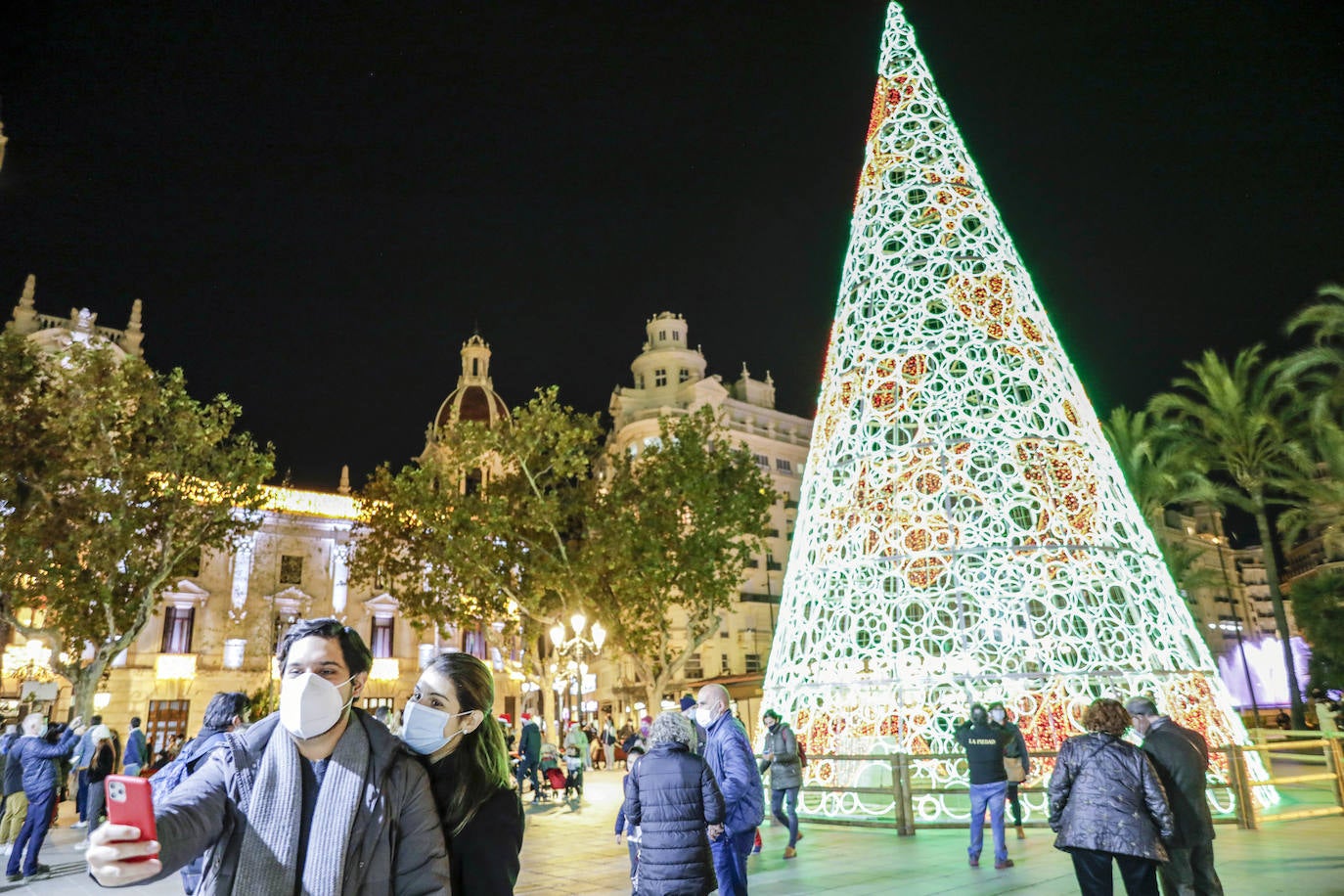 El alcalde Ribó ha asistido esta tarde al encendido en la plaza del Ayuntamiento, acompañado por las falleras mayores de Valencia, Consuelo Llobell y Carla García. La iluminación se estrena en la ciudad con quejas por el escaso gasto frente al aumento en otras ciudades para ayudar al comercio.