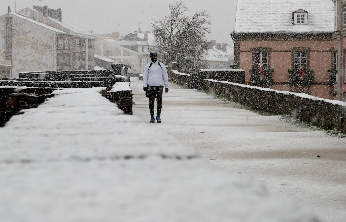 Una persona pasea por el paisaje nevado de la Muralla Romana de Lugo.