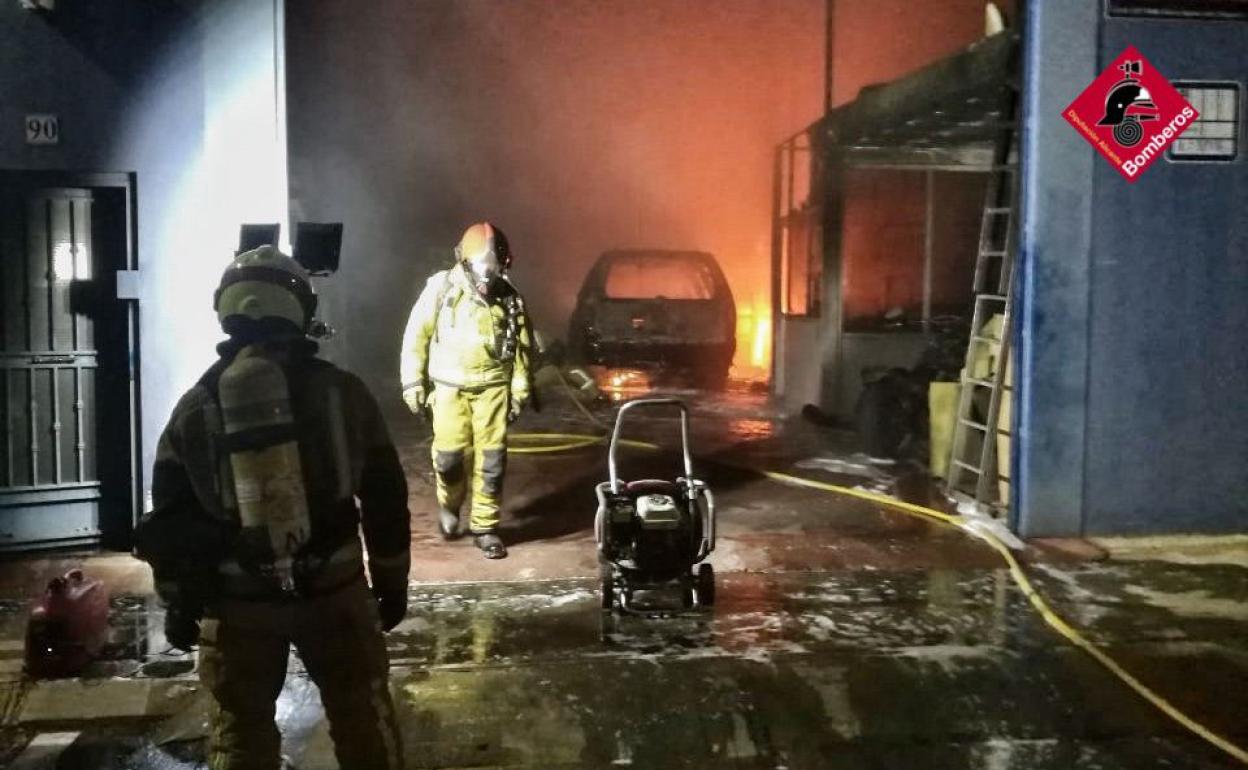 Los bomberos tratan de controlar el fuego en el taller de automoción de Guardamar. 