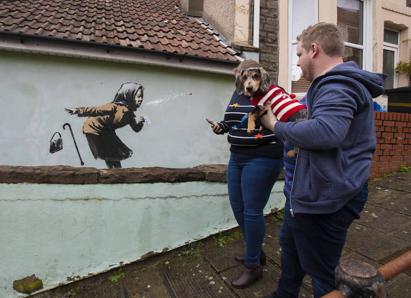 Bristol ha amanecido con una sorpresa: un nuevo mural del popular y misterioso artista urbano Banksy. La pintura titulada 'Aachoo!!' representa a una anciana estornudando, con su dentadura postiza volando, y apareció en la calle Vale Street durante la madrugada del jueves. 