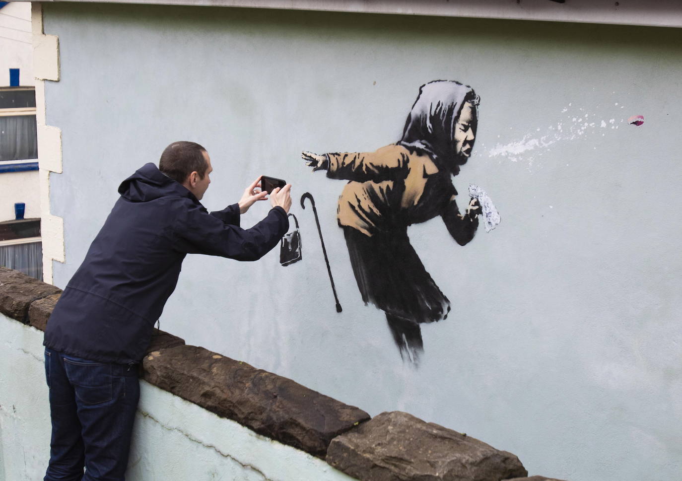 Bristol ha amanecido con una sorpresa: un nuevo mural del popular y misterioso artista urbano Banksy. La pintura titulada 'Aachoo!!' representa a una anciana estornudando, con su dentadura postiza volando, y apareció en la calle Vale Street durante la madrugada del jueves. 