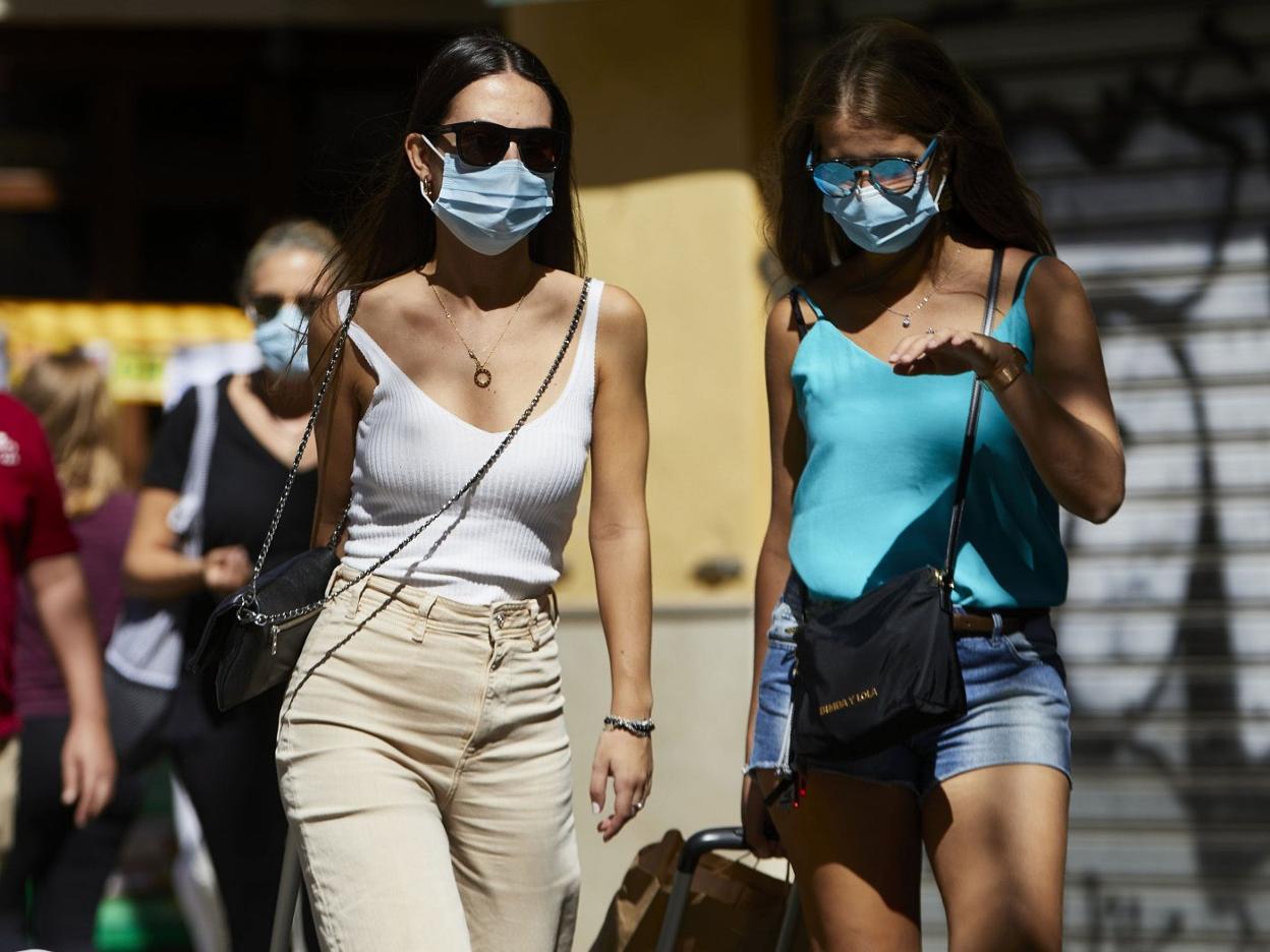 Dos jóvenes pasean por una calle de Valencia