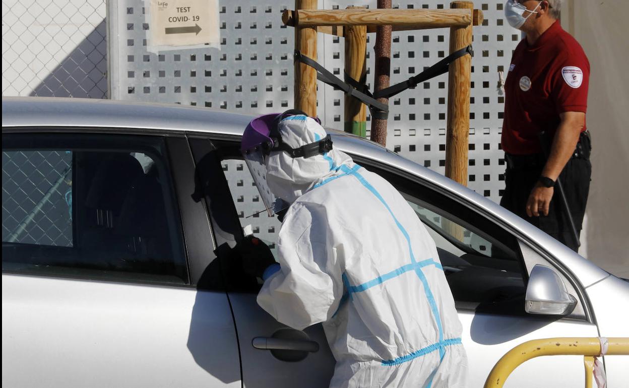 Un sanitario realiza una prueba PCR frente a La Fe.