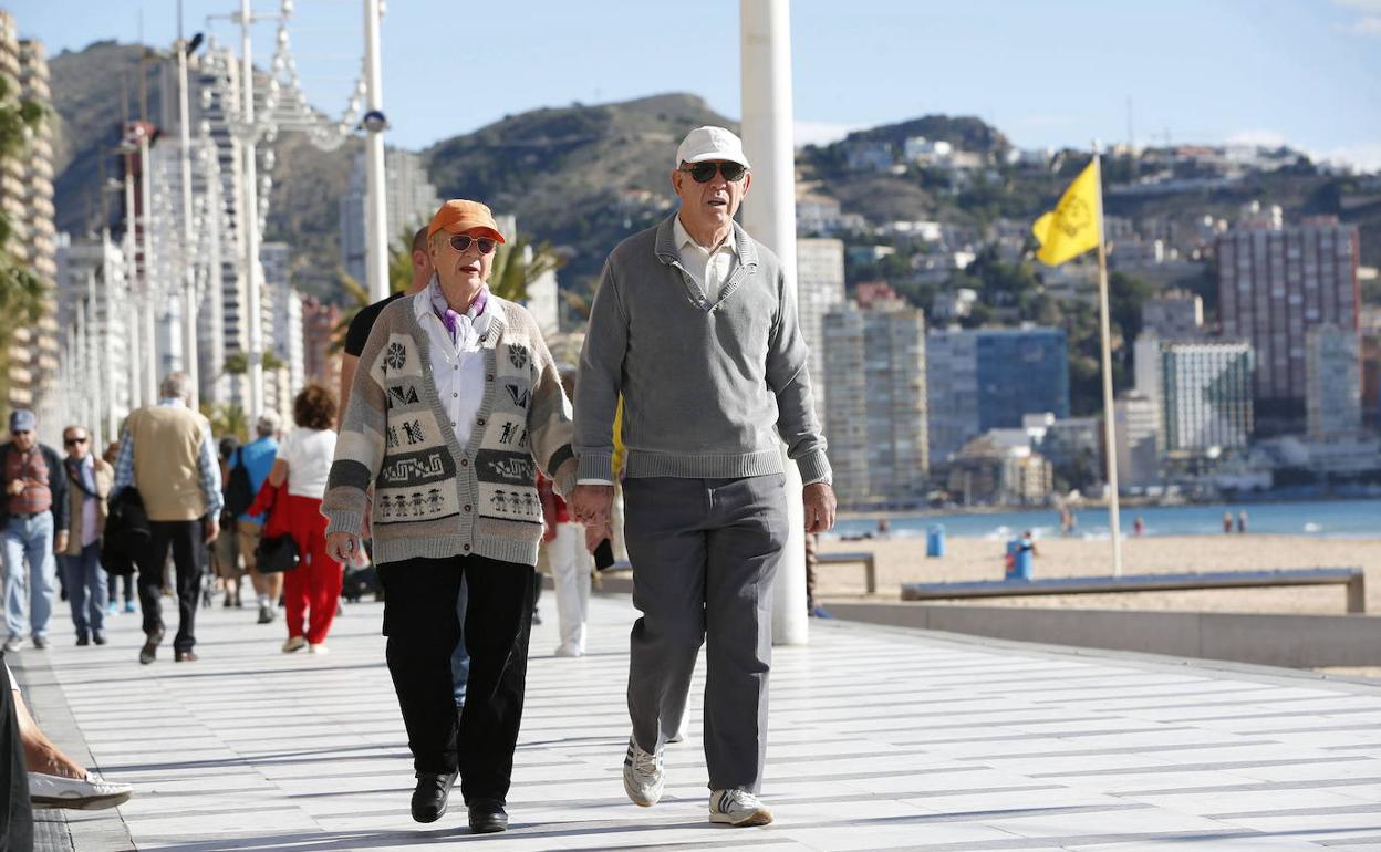 Dos jubilados pasean por un paseo marítimo. 