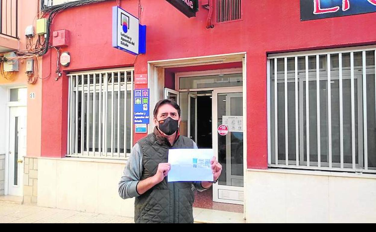 Ramón Ferri, delante del bar mostrando el décimo agraciado.
