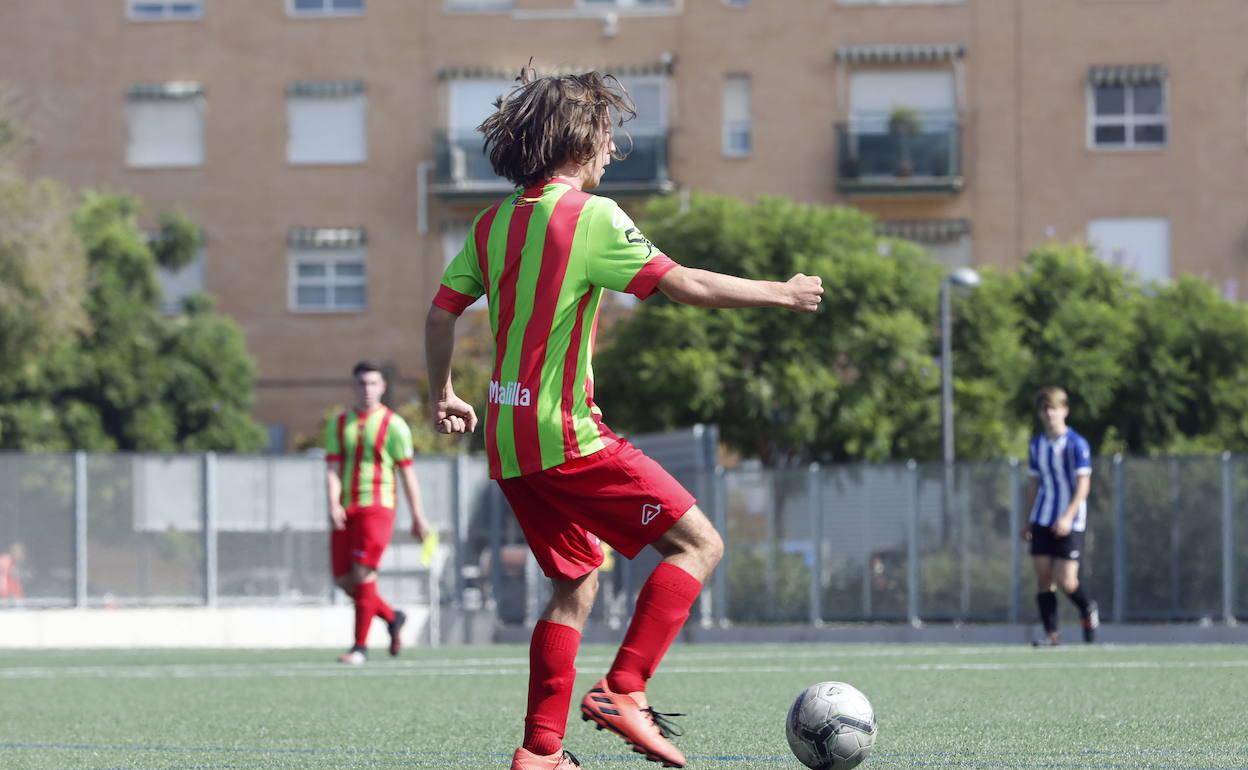 Un chaval controla el balón durante un partido de fútbol base. 