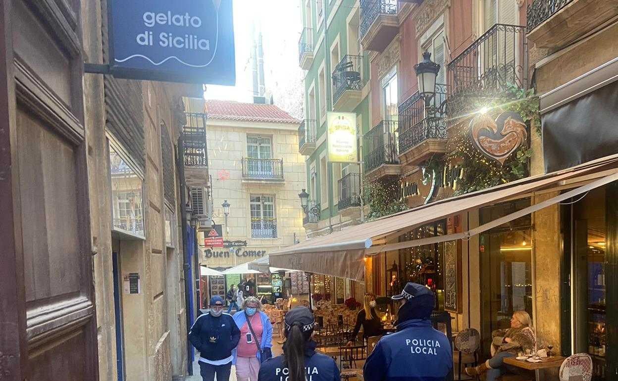 Una pareja de agentes vigila una terraza situada en una de las calles peatonales del centro de Alicante. 