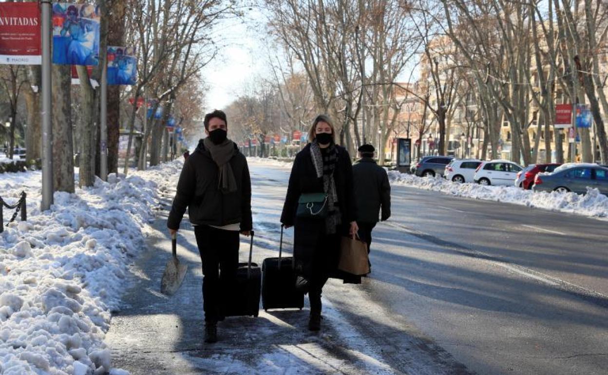 Dos viajeros con mascarilla caminan por la calzada en Madrid 