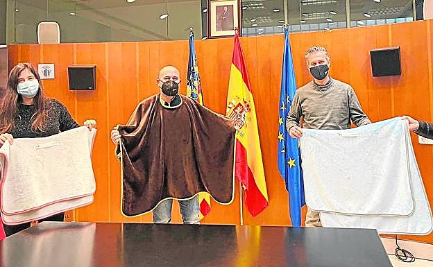 El alcalde y los concejales muestran las prendas de abrigo.