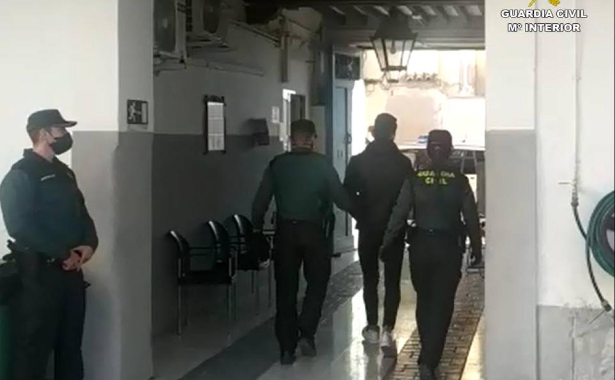 Los agentes conducen a uno de los detenidos. 