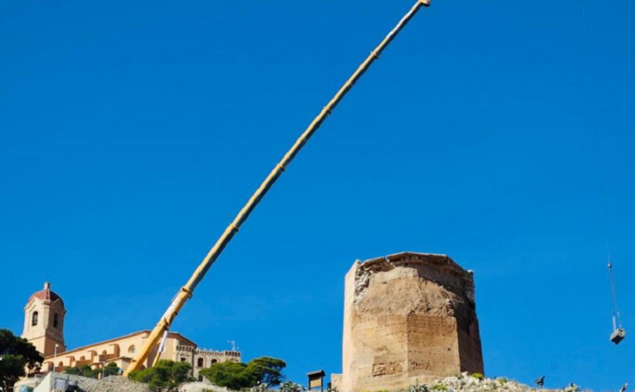 Una grúa está transportando los materiales junto a la Torre que será restaurada. 