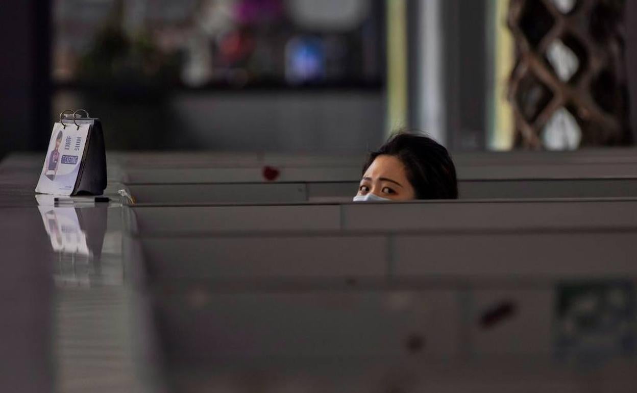 Una empleada asoma apenas la cabeza de su cubículo en el aeropuerto de Shanghai. 