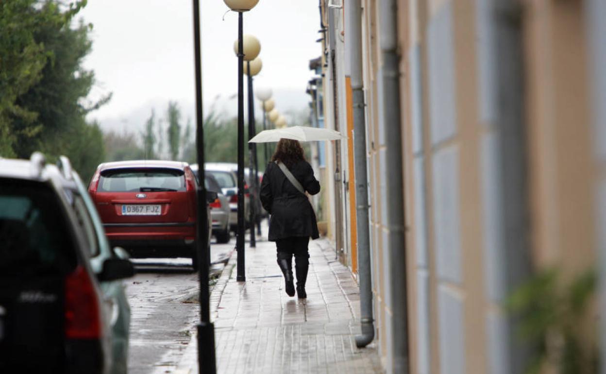 Una mujer con un paraguas paseando por La Pobla Llarga.