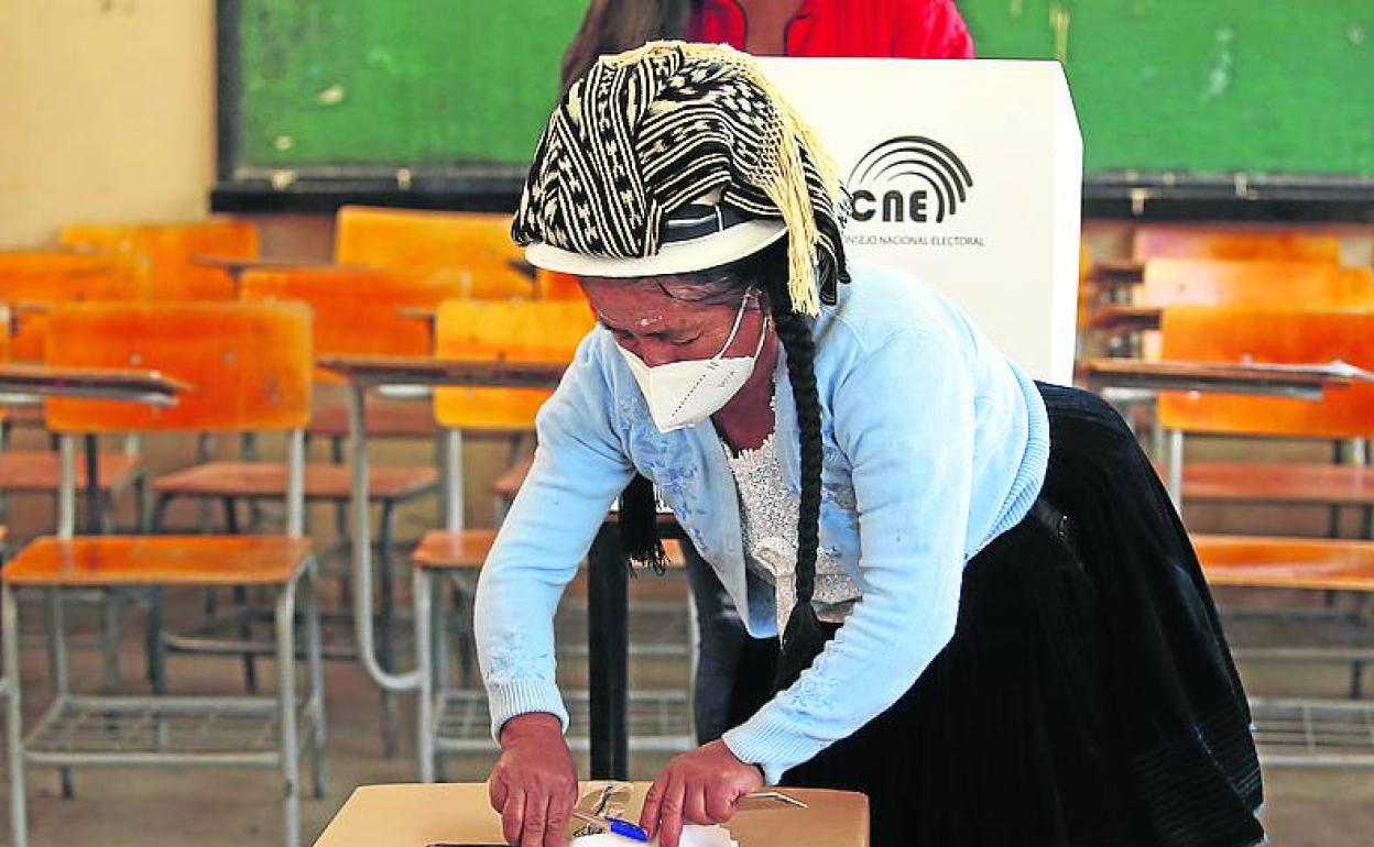 Una mujer prepara el material para las votaciones en un colegio.