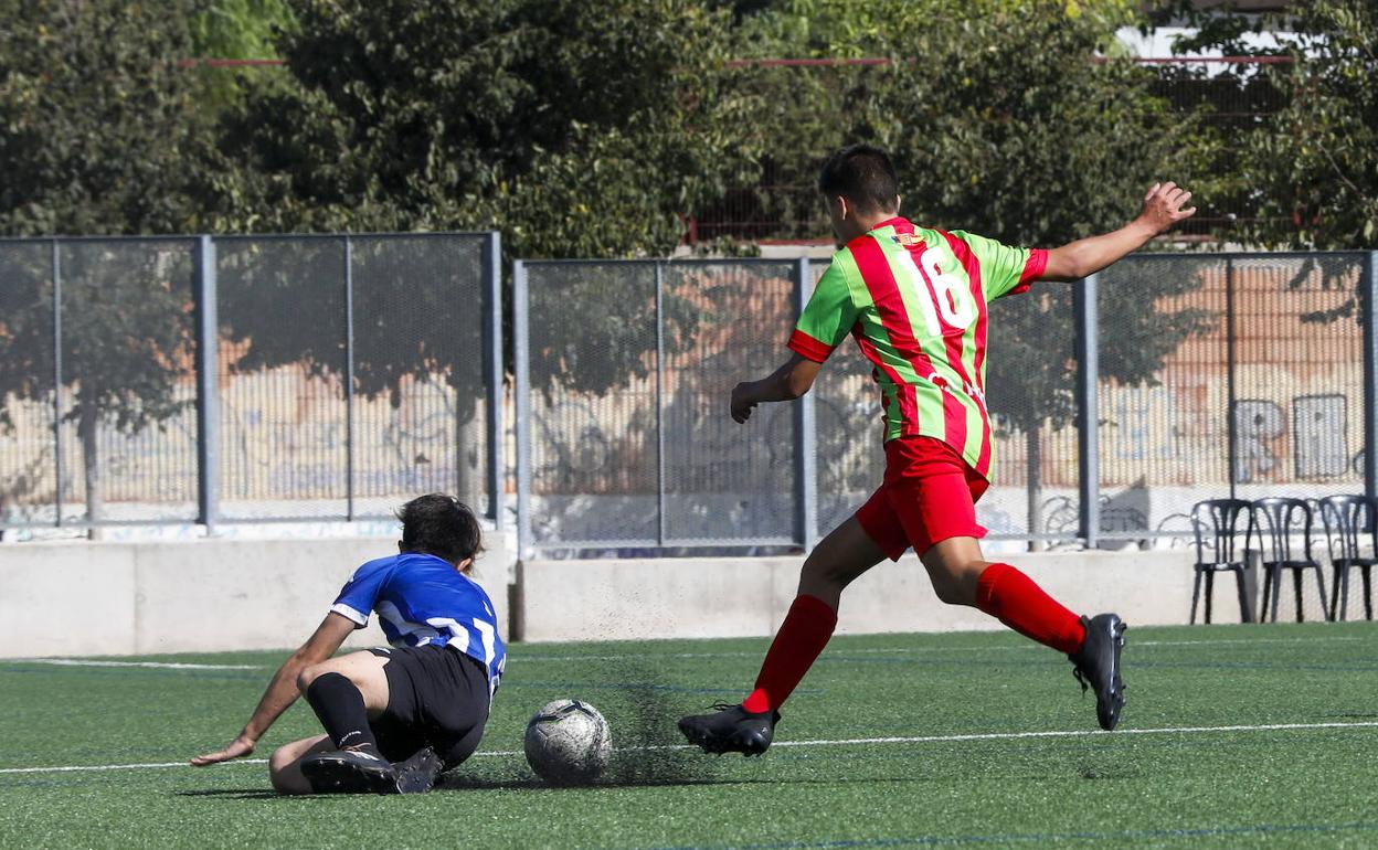 Dos chavales disputan un partido de fútbol. 