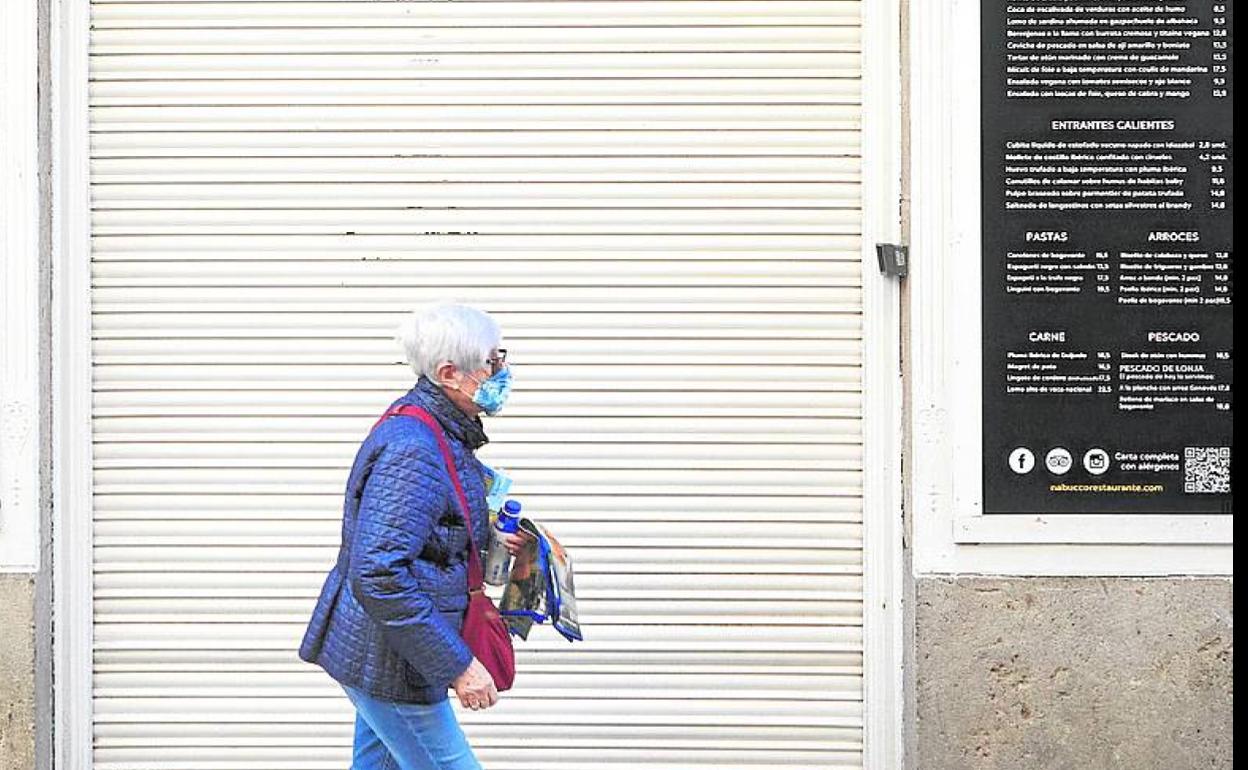 Una mujer pasa por delante de un local cerrado. 