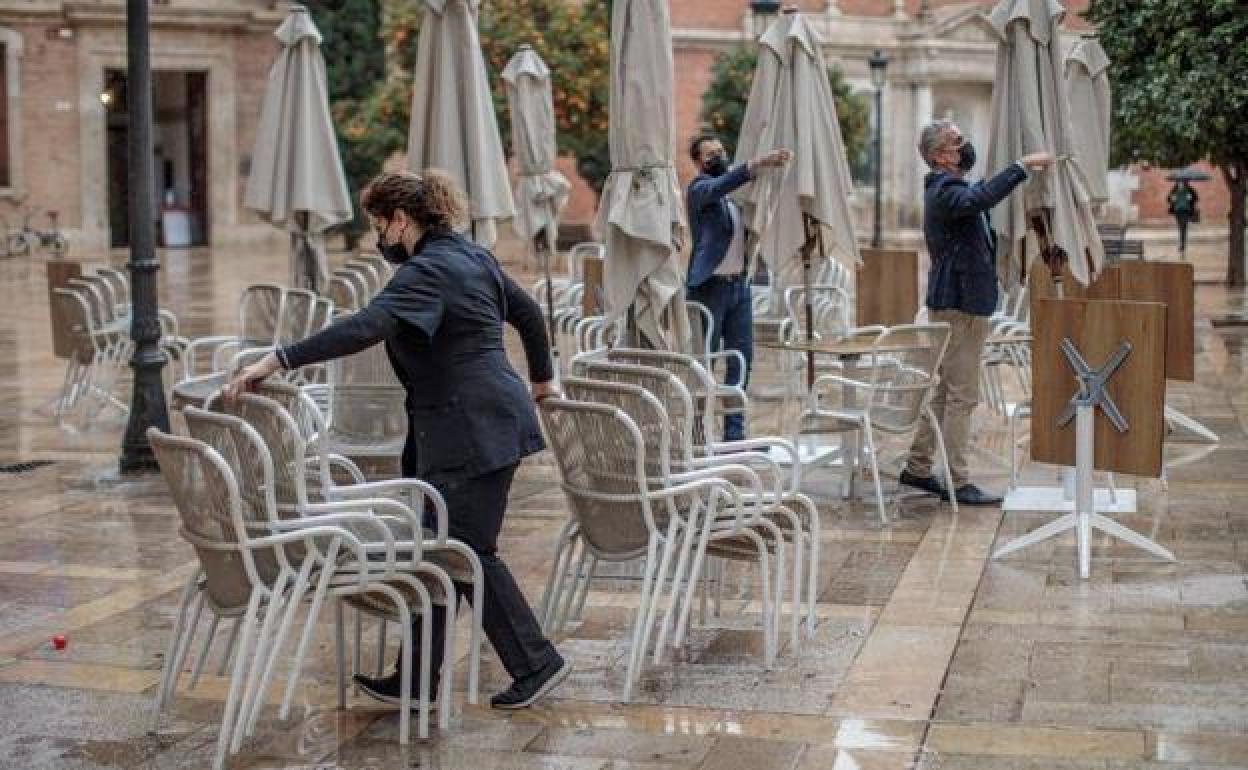 Unos trabajadores de un restaurante del centro de Valencia recogen la terraza.