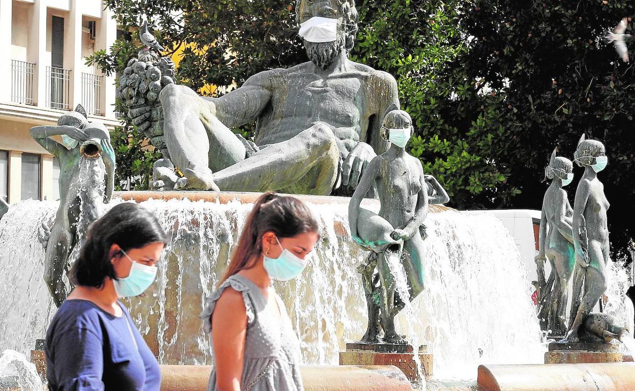 Dos mujeres pasan ante la fuente de la plaza de la Virgen. 