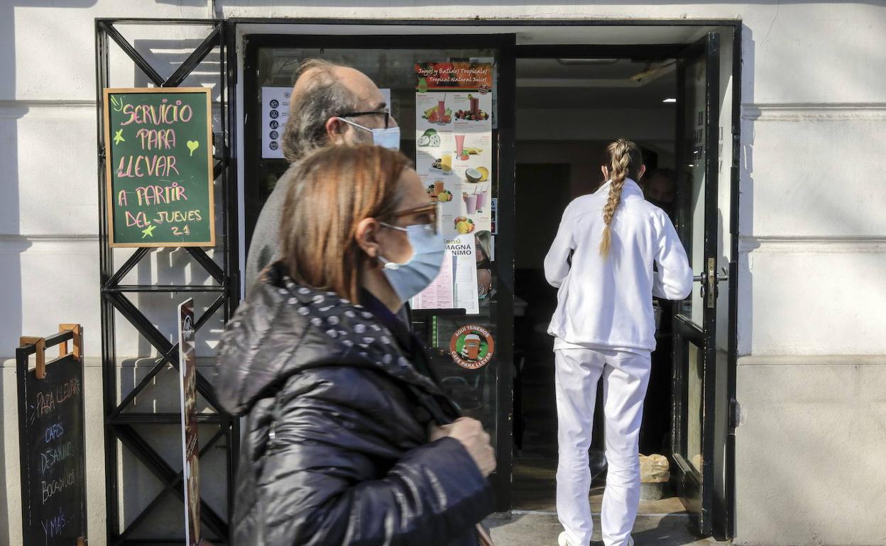 Personas ante un bar cerrado de Valencia