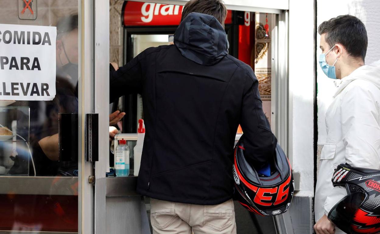 Dos personas compran comida para llevar en un bar de Valencia. 