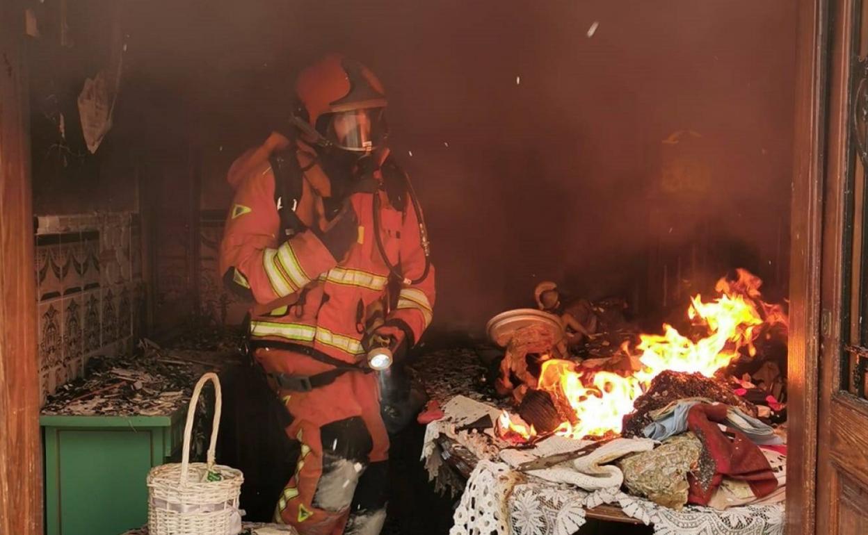 Un bombero apagando el fuego en una de las estancias de la vivienda. 