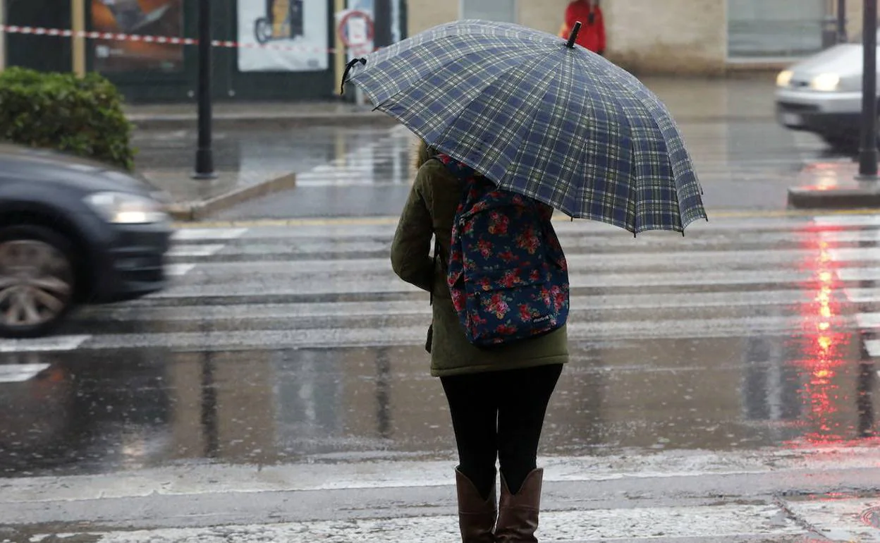 Una joven se refugia de la lluvia en Valencia