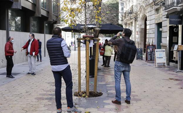 Personas tomando un refresco frente a un bar en Valencia.