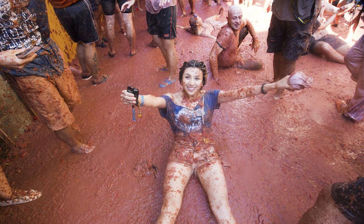 Varias personas disfrutan de una de las últimas ediciones de la Tomatina de Buñol.