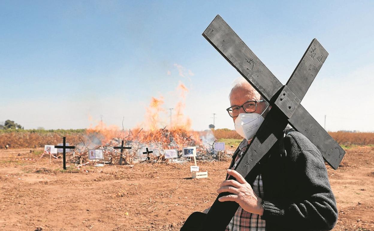 Un agricultor con una cruz, ayer, en la protesta por los bajos precios ante la hoguera en un campo de Algemesí. 