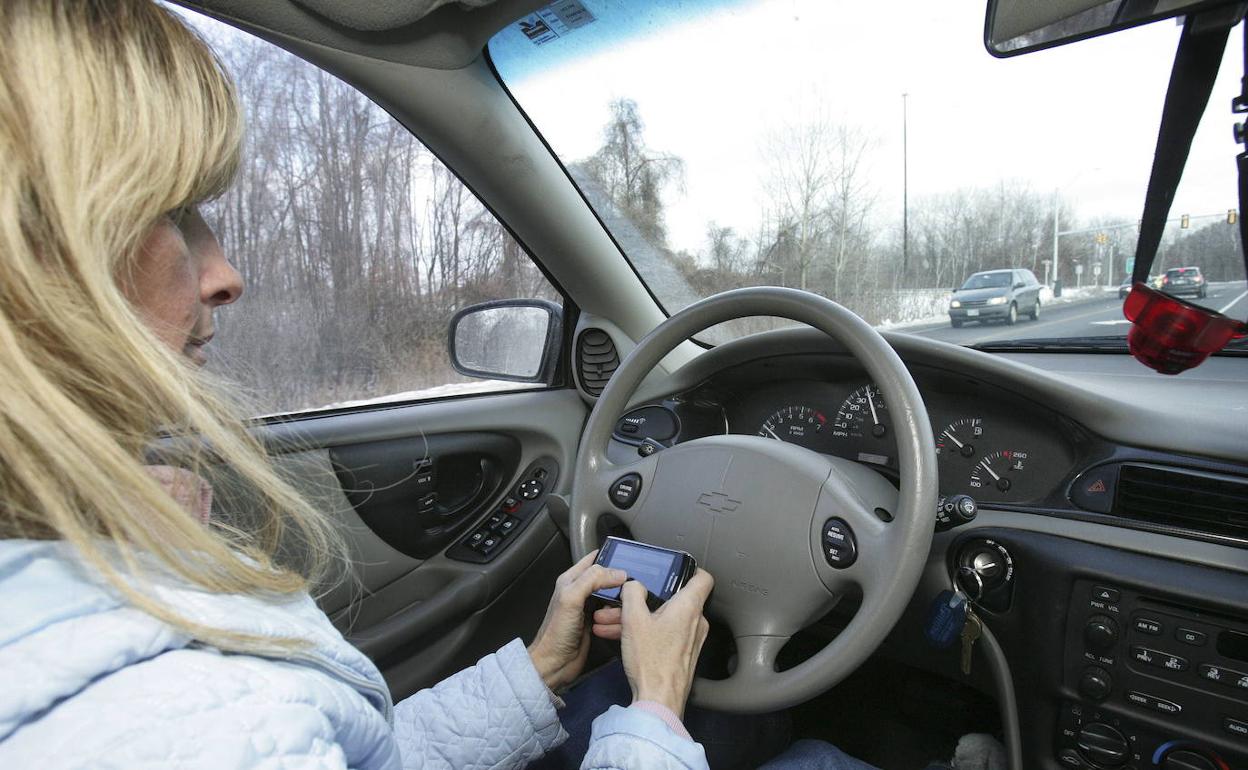 Una mujer usa el móvil en el coche. 