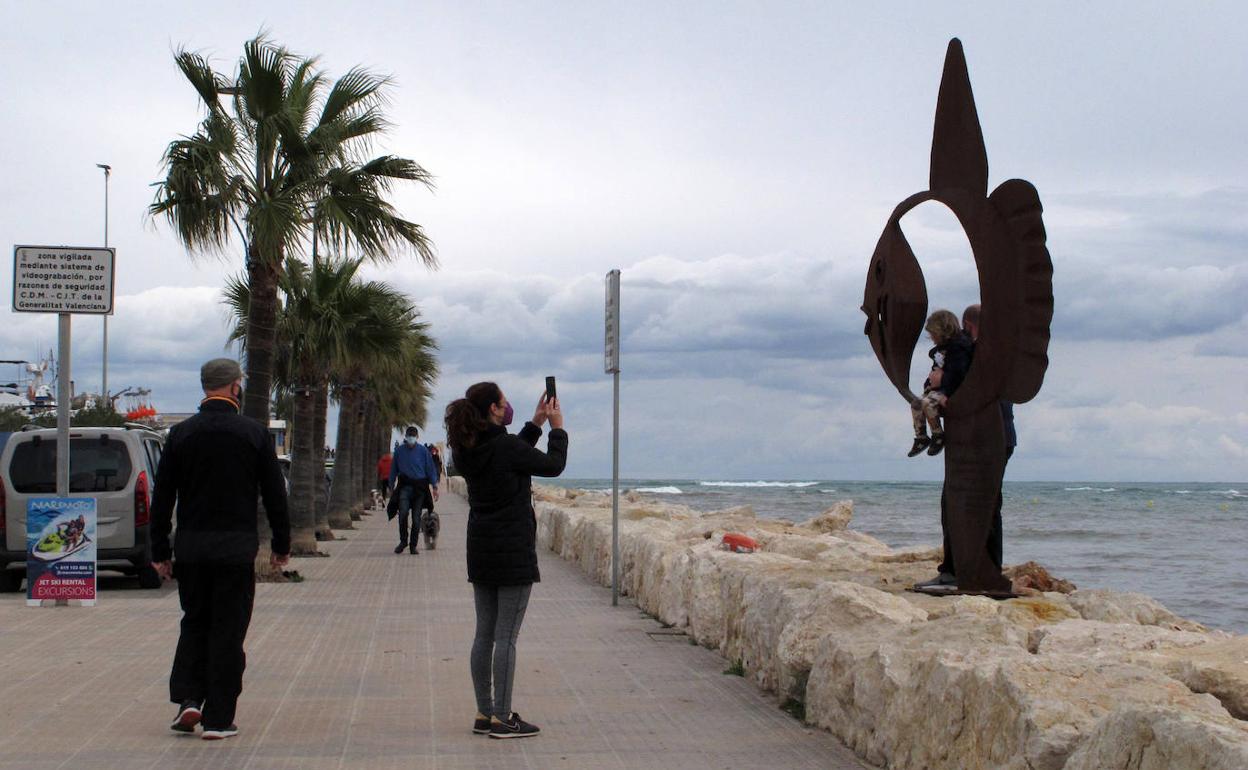 Una madre fotografía a su familia junto a una escultura en el paseo de acceso al puerto deportivo Marina de Dénia. 