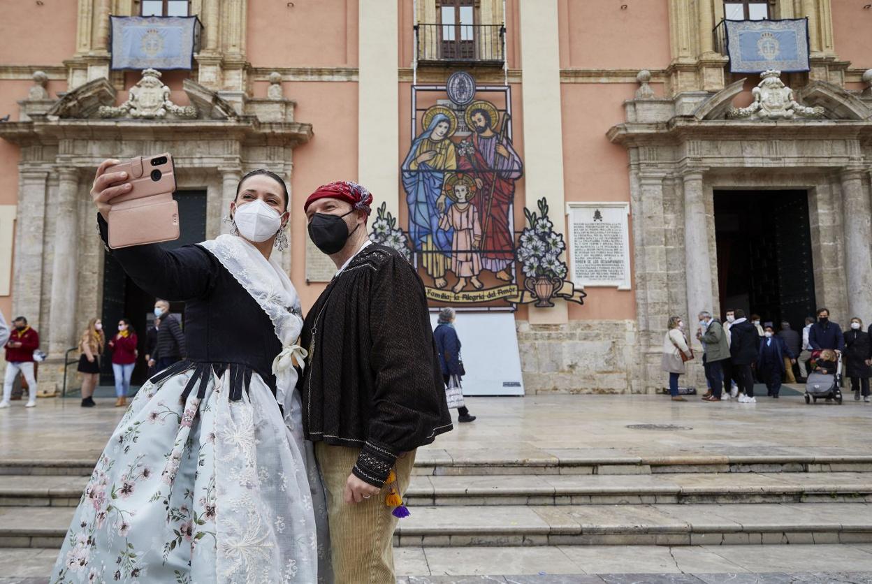 Una pareja vestida de valencianos se fotografía ante la Basílica, ayer en la plaza de la Virgen. ivan arlandis