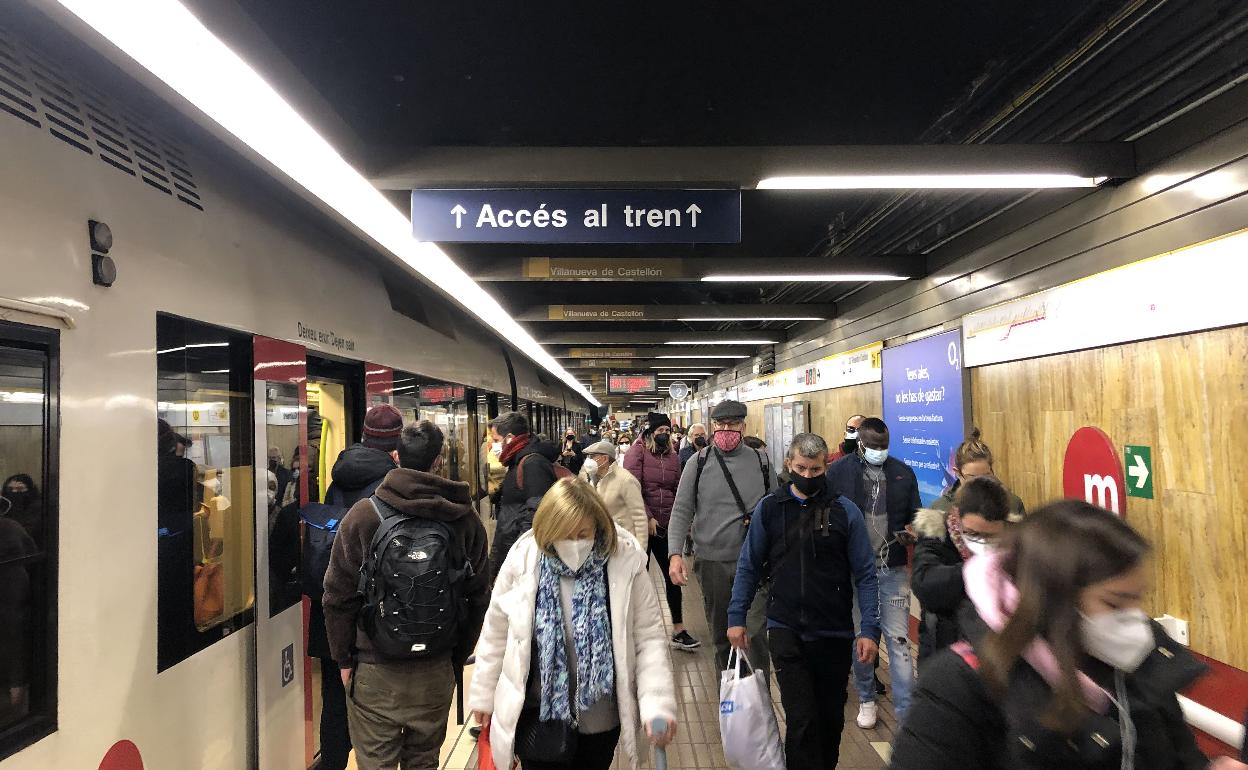 Varias personas caminan junto a un vagón de metro en Valencia. 