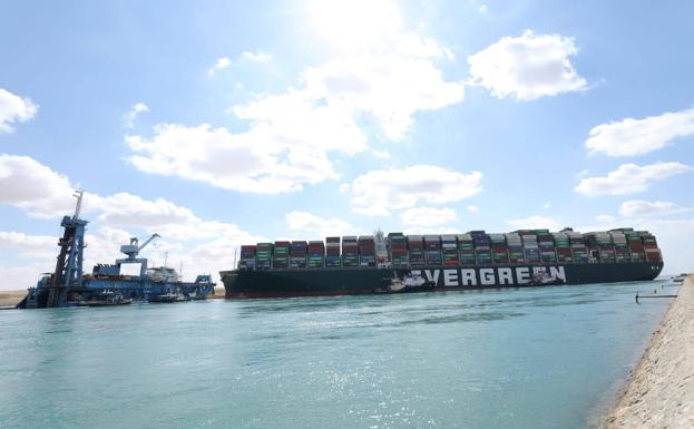 El portacontenedores Ever Given, atravesado en el canal de Suez y vigilado por los remolcadores y una draga.