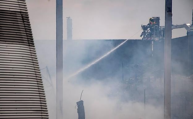 Un bombero refresca la zona afectada por el fuego en el polígono industrial de Seseña (Toledo).