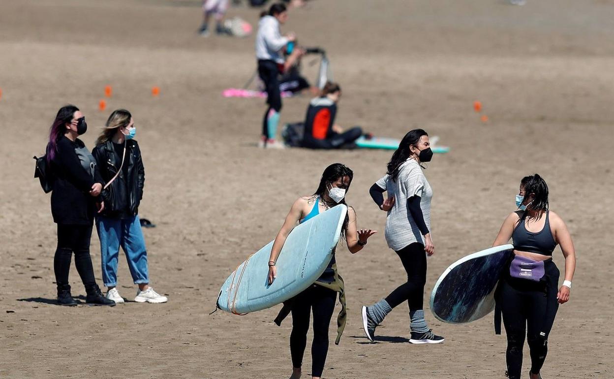 Un grupo de jóvenes, con mascarillas en una playa de Valencia