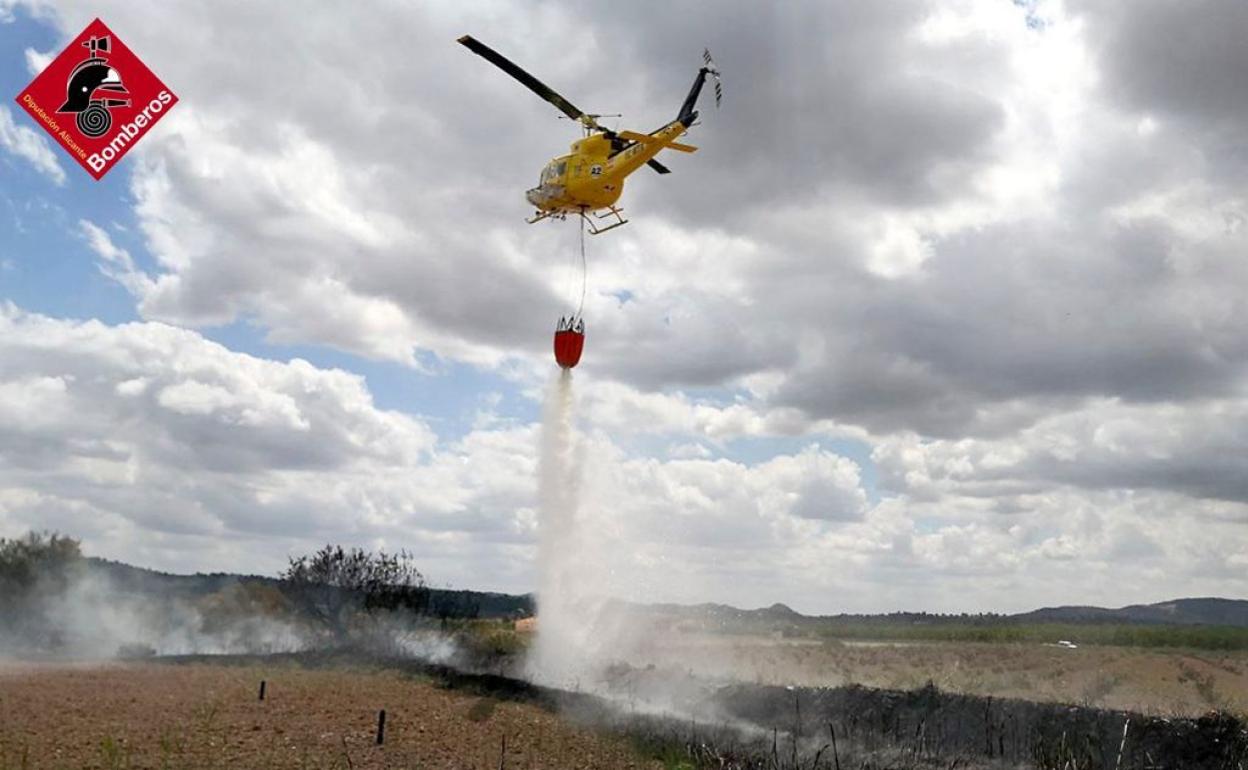 El helicóptero descarga agua para sofocar el incendio en Pinoso. 