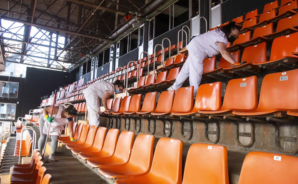 Operarias ponen a punto los asientos para el deseado regreso de la afición. 