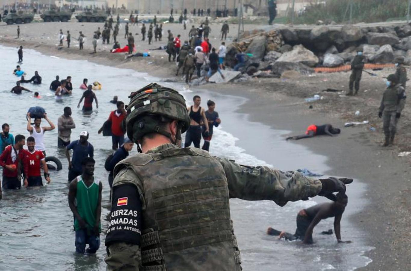 Un legionario español indica la dirección a seguir a los ciudadanos marroquíes en la playa de El Tarajal.